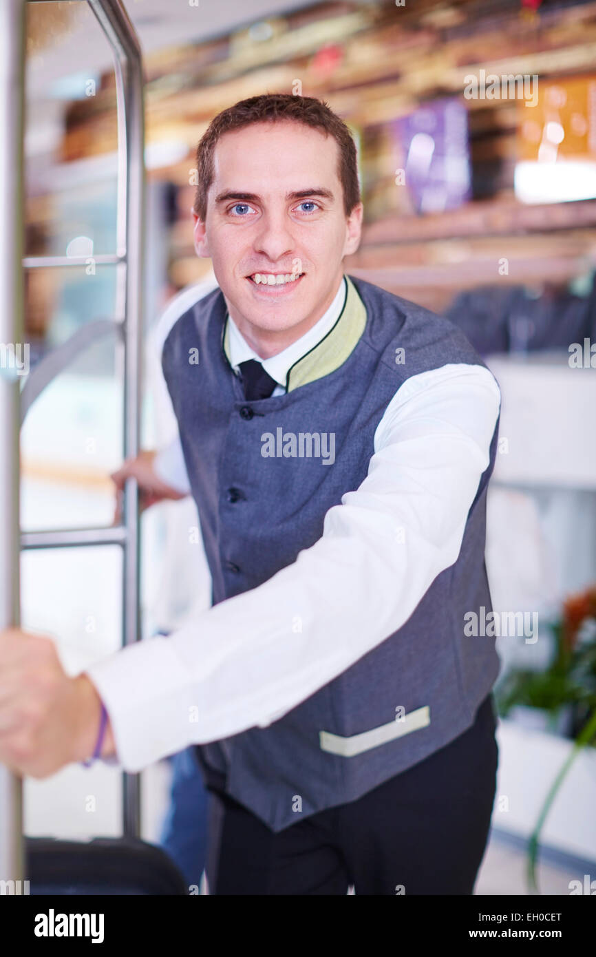Hotel bell boy in lobby with luggage cart Stock Photo Alamy