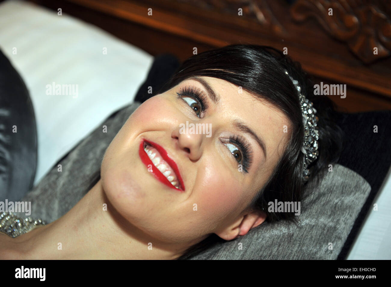 women with full makeup lying on a pillow smiling MODEL RELEASED Stock Photo
