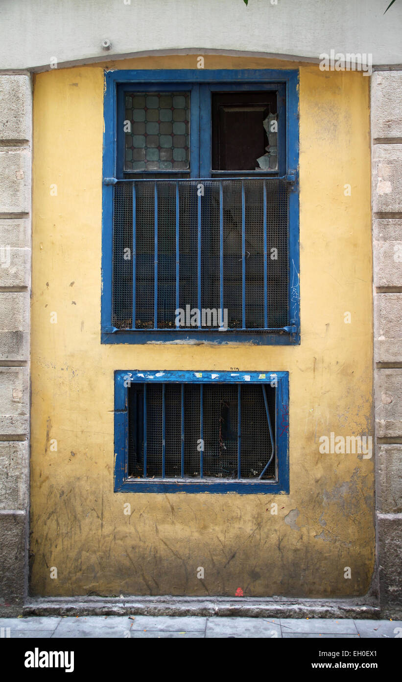 Old window with bars and broken pane of glass in street in El Raval neighbourhood in the centre of Barcelona Stock Photo
