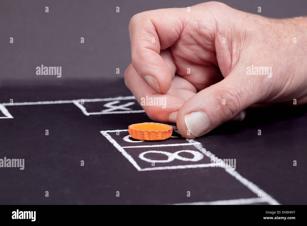Player flicking the cap to the next number in the game of Skully. Stock Photo
