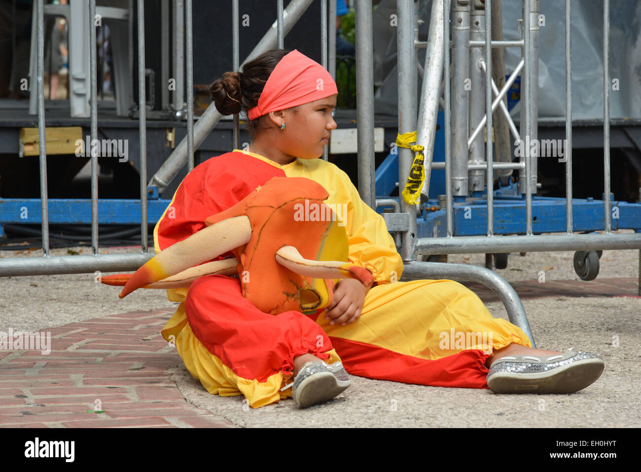 Young girl in a Vejigante costume sitting down at Plaza de las Delicias during carnival festivities in Ponce, Puerto Rico. Stock Photo