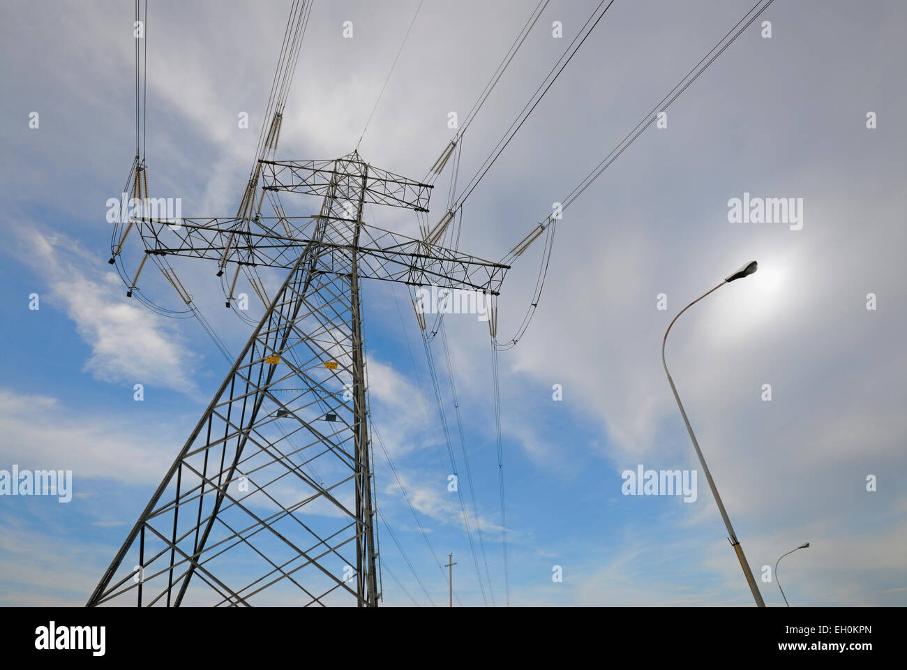 High voltage power supply lines and steel pylon next to street light ...