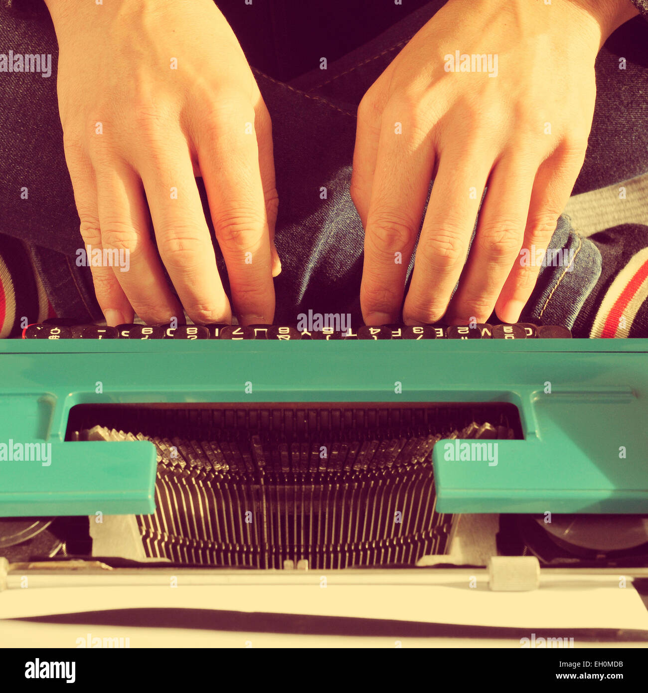 a young man typing in an old typewriter on the bed, with a retro effect Stock Photo