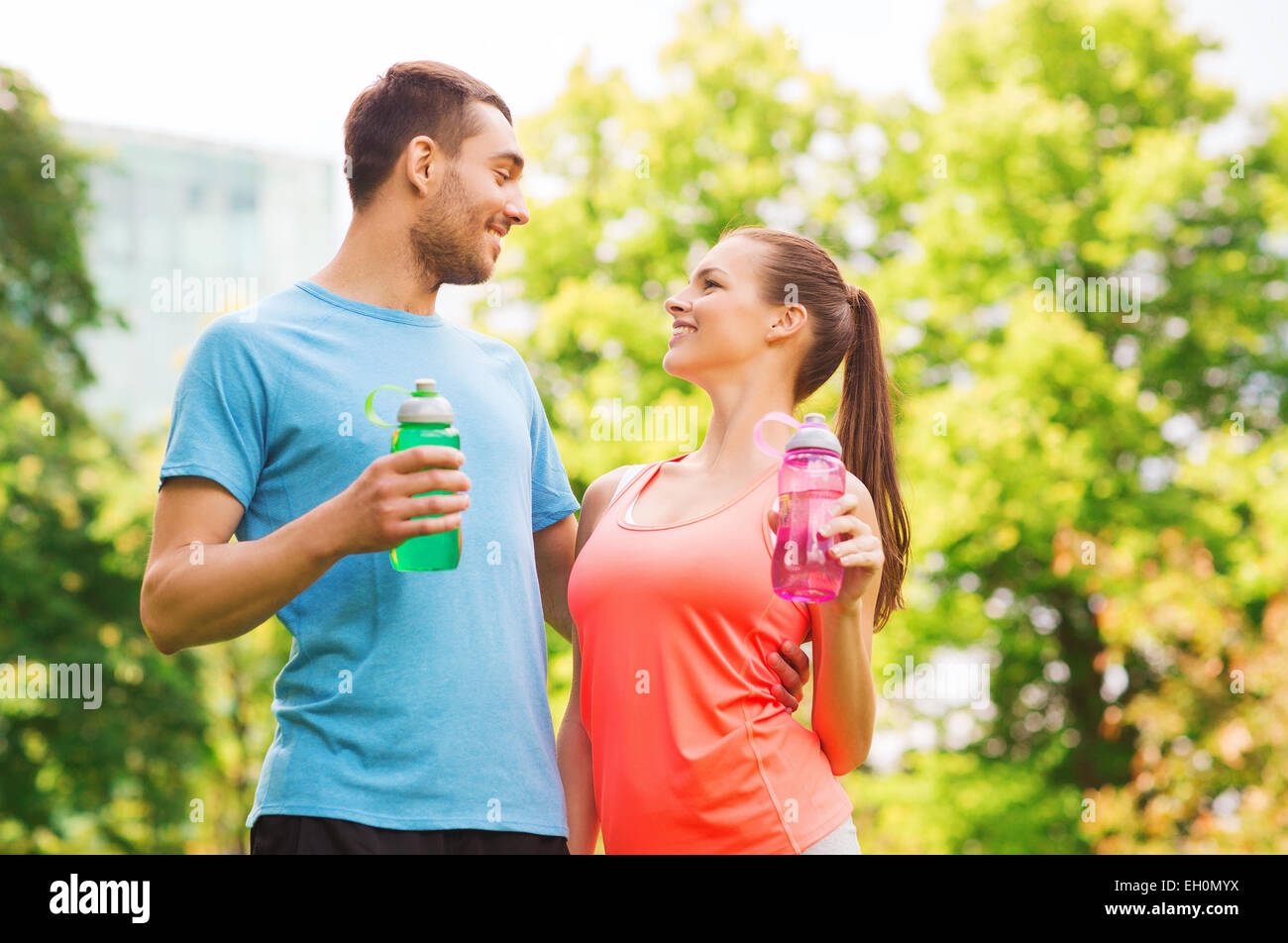 smiling couple with bottles of water outdoors Stock Photo