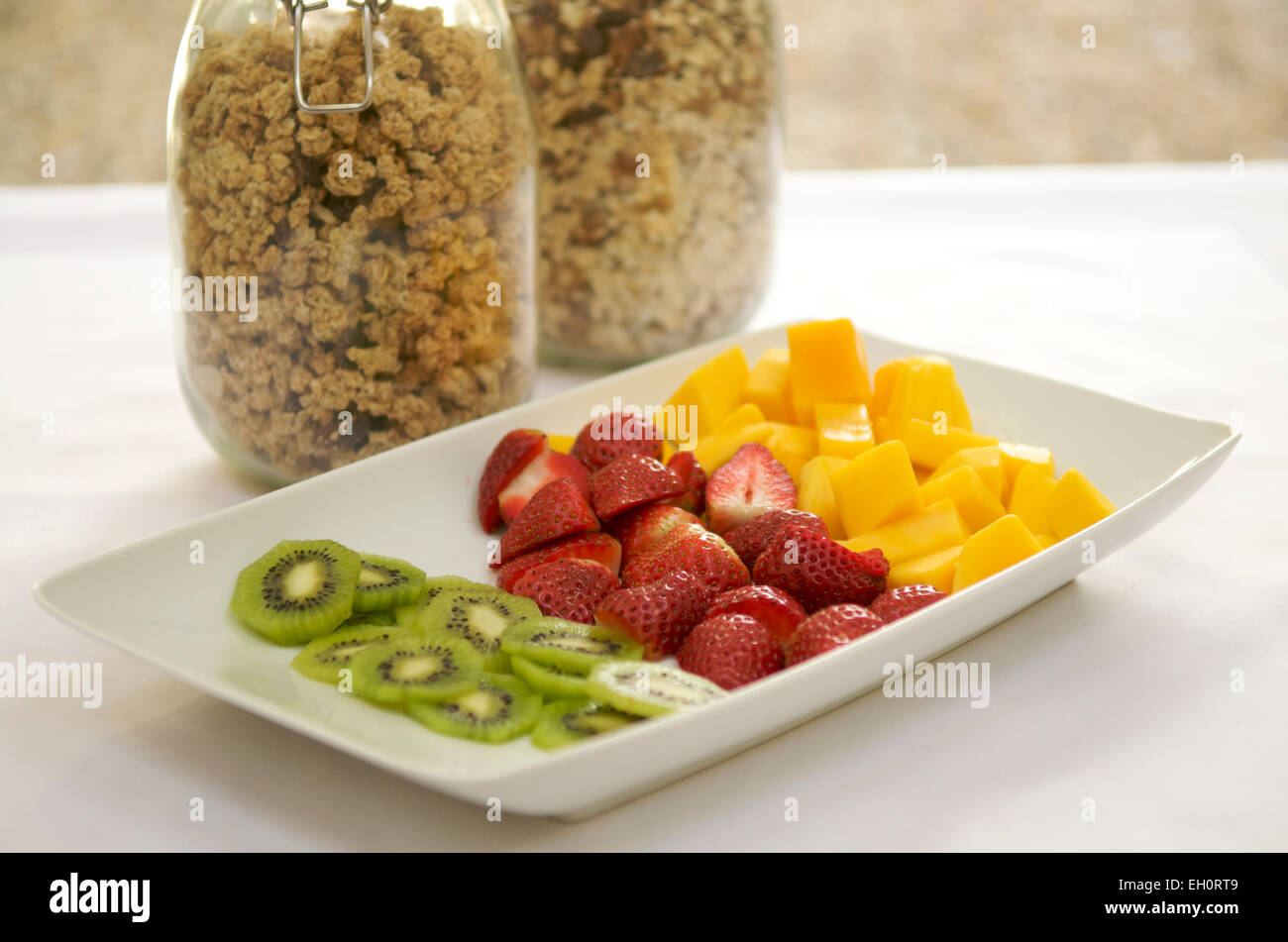 Selection of fruits with jars of granola and muesli at breakfast Stock