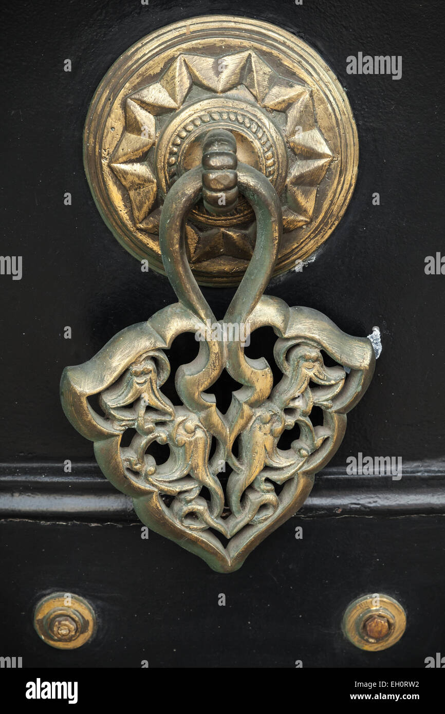 Old copper door knob with Arabic pattern on black wooden gate. Izmir