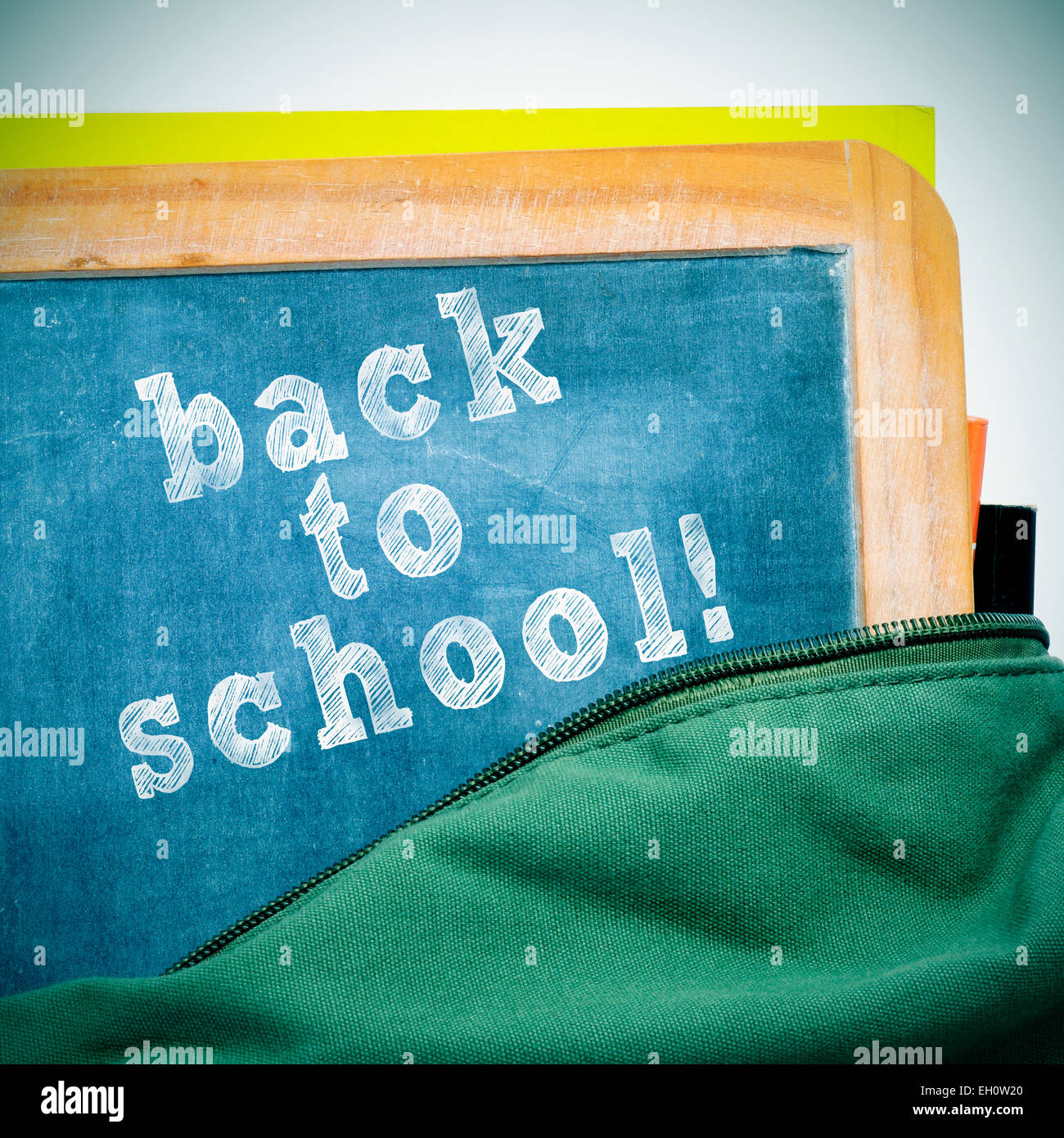 sentence back to school written in a blackboard with a wooden frame, in a schoolbag, with a retro effect Stock Photo