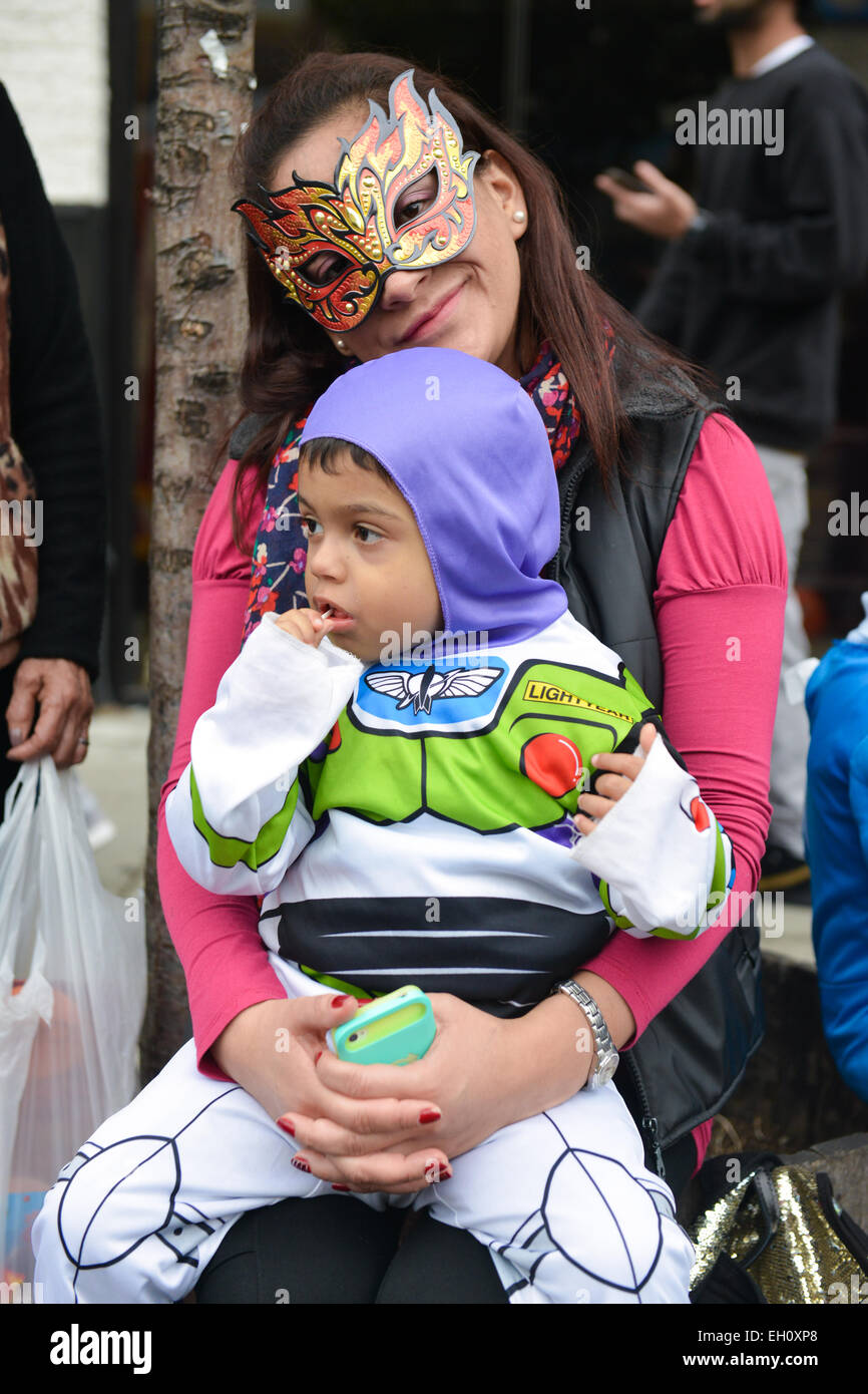 Masked young mother holding on her lap her young son dressed up as Buzz Lightyear during Halloween 2013. Newark, New Jersey USA. Stock Photo