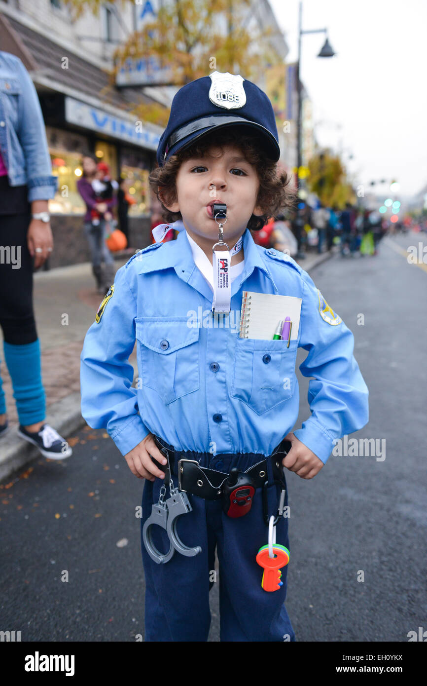 Young boy dressed as a police officer in the streets of Newark, New Jersey during Halloween 2013 with people on the background. Stock Photo