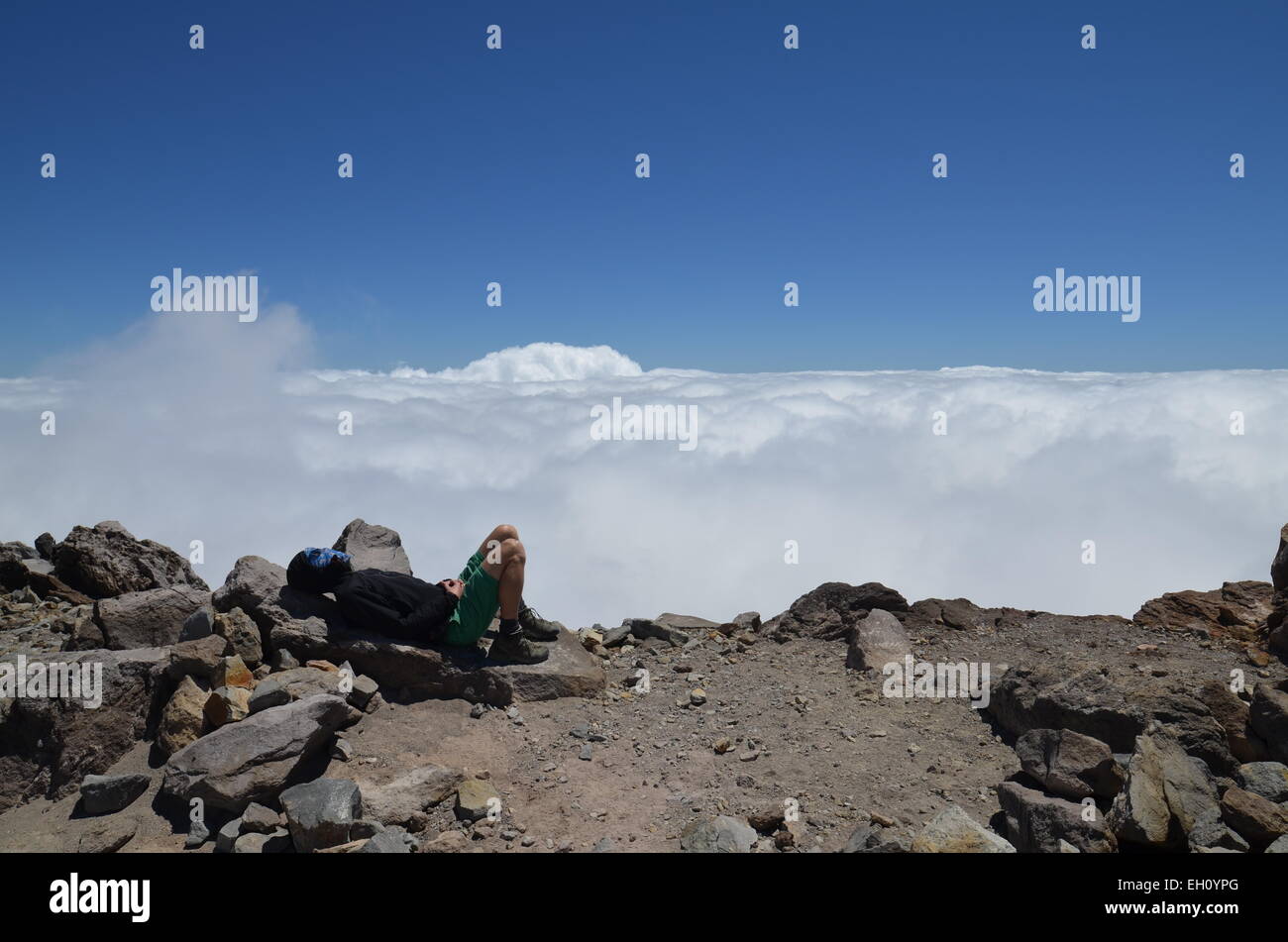 Resting on the summit of Mount Taranaki above the clouds Stock Photo