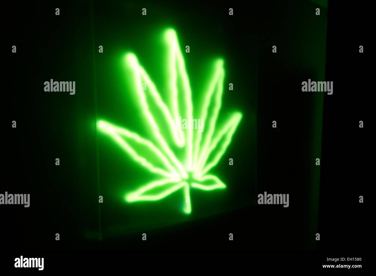 Neon cannabis leaf retail sign on urban storefront drug dispensary at night. Alternative medicine, chronic pain relief. Stock Photo