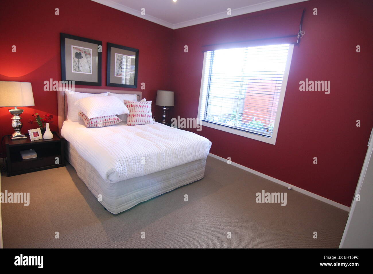 Modern Bedroom With Double Bed And Dark Red Wall Stock Photo