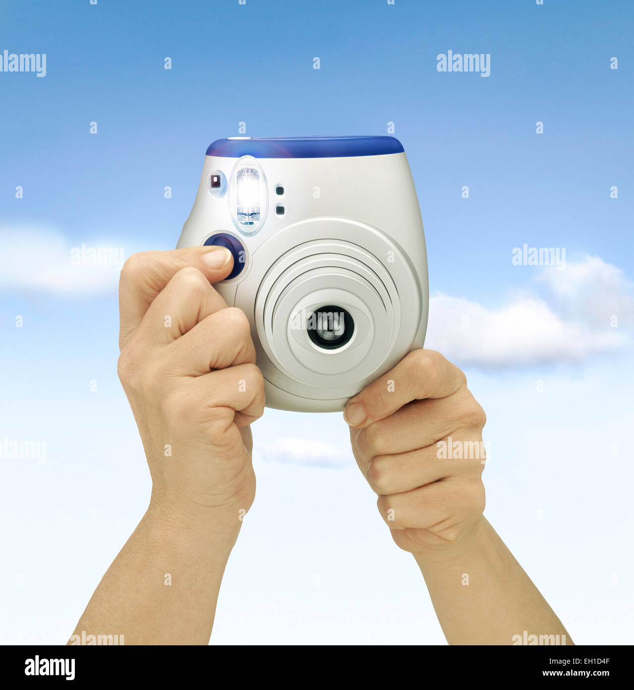 Hand Holding Camera against blue sky. Flashing shot. Clipping path Stock Photo