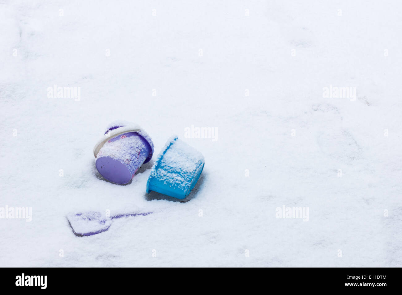 Children's toys left behind on a snowy ground, copy space. Stock Photo