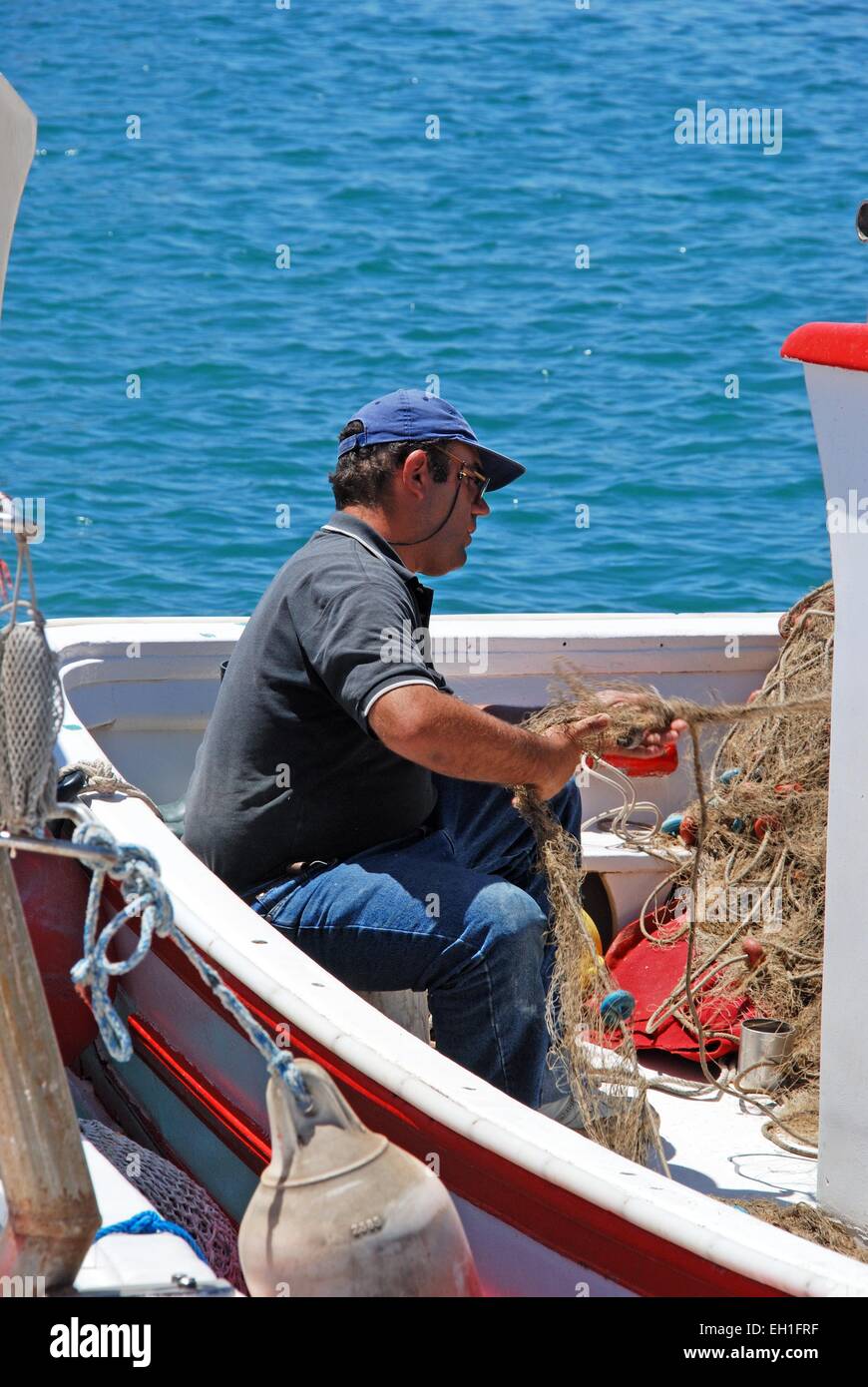 Spanish fisherman tending to his nets on traditional fishing boats in the harbour, Garrucha