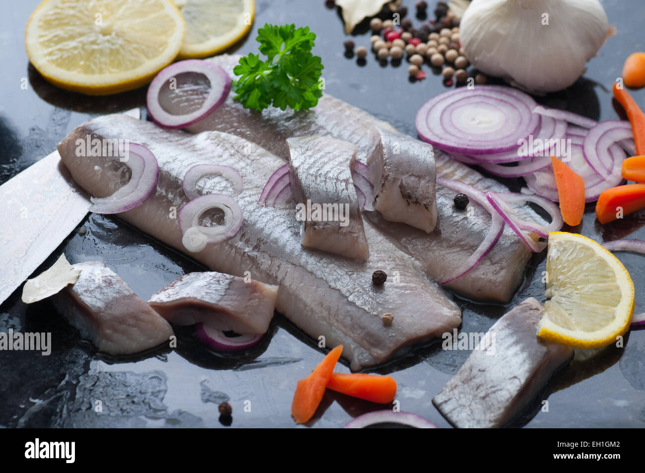 Pickled herring fillet with spices, carrot, onion and lemon. Stock Photo