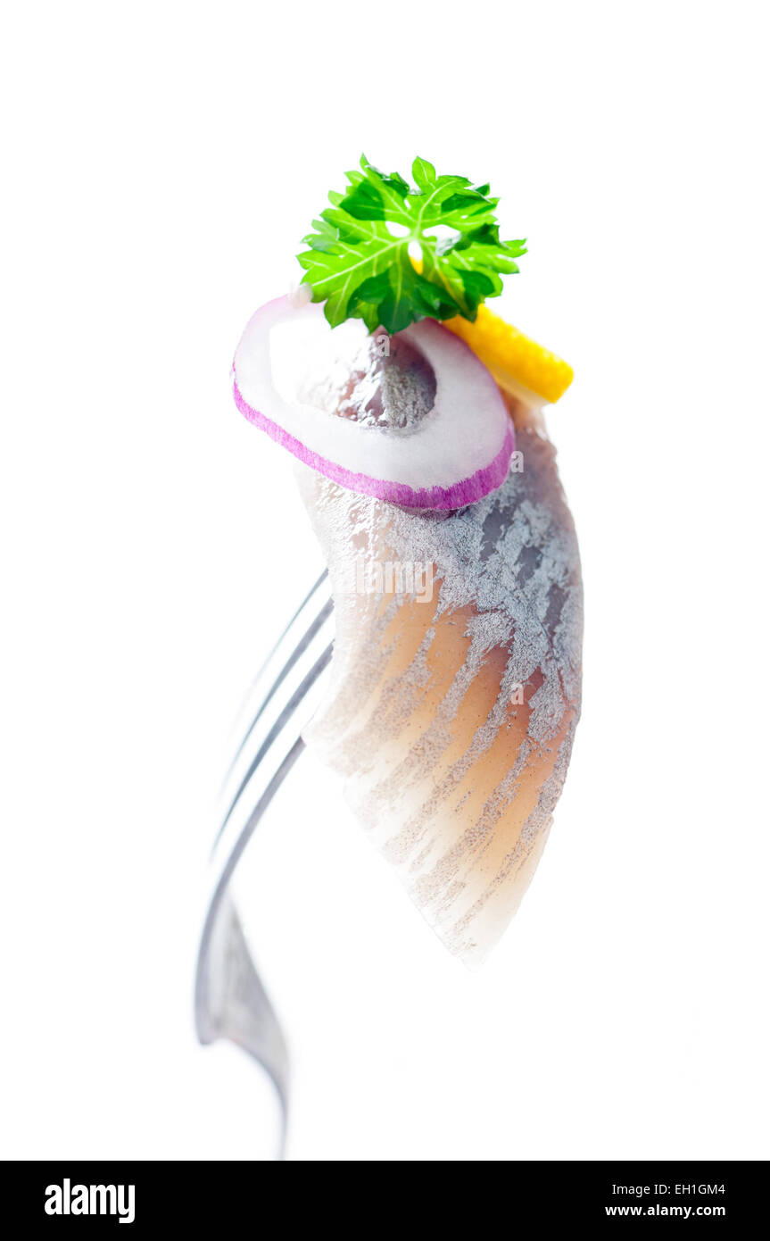 A piece of pickled herring on a fork. Stock Photo