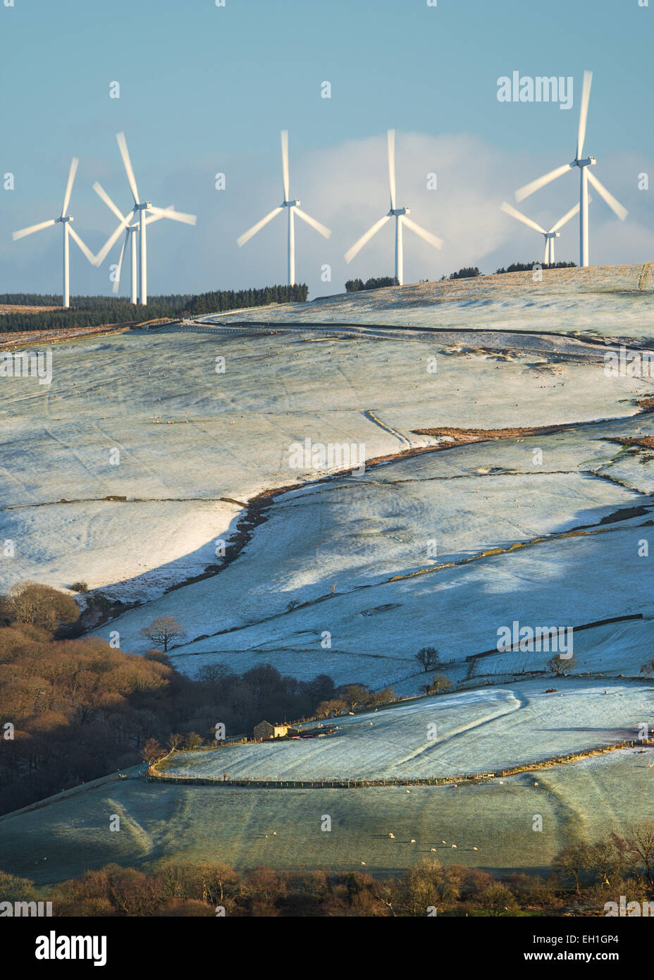 A wind farm on agricultural land in on a frosty morning in south Wales, there is a small barn just below. Stock Photo