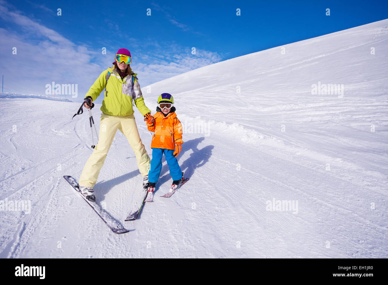 Mother and little boy learning to ski holding hand Stock Photo