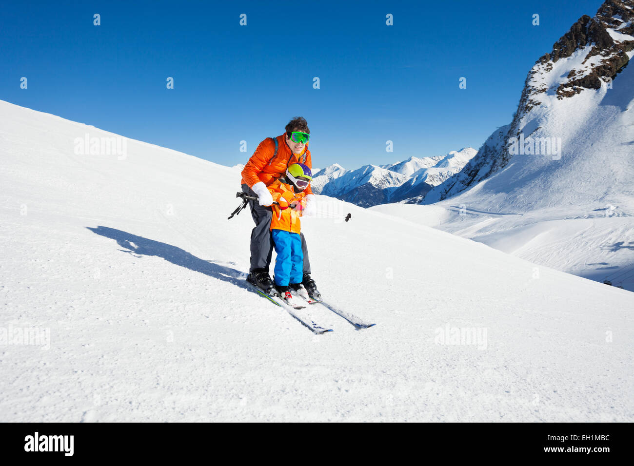 Dad teach little son to ski in mountains Stock Photo