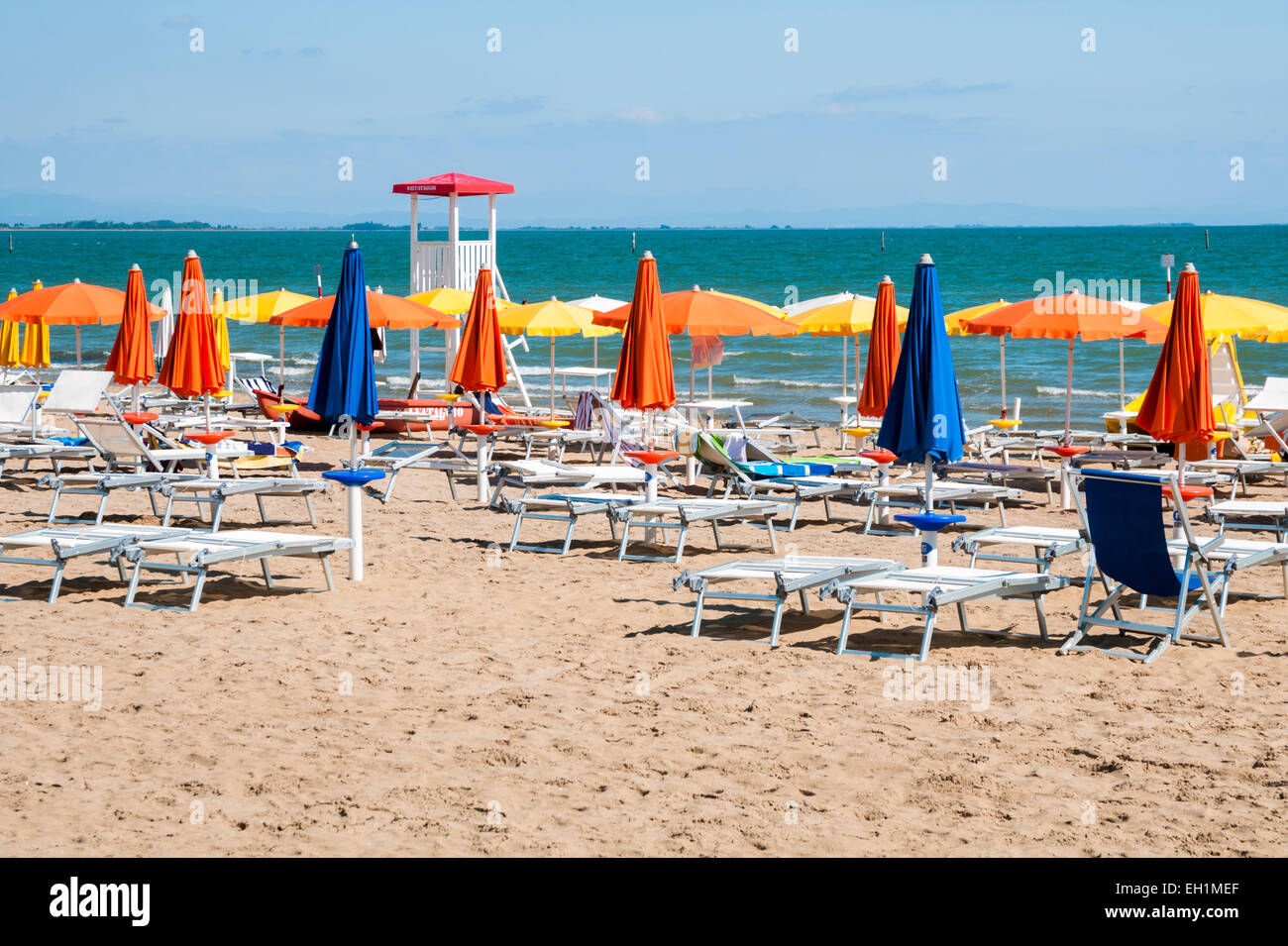 Sandy beach with colorful umbrellas, chairs and lifegard tower Stock Photo