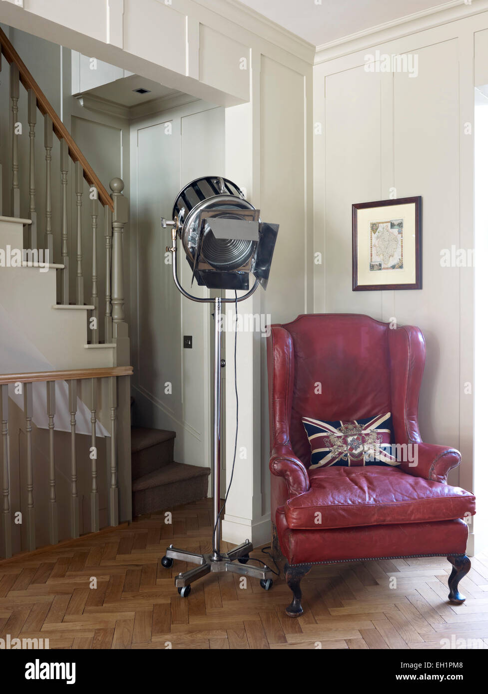 Red leather armchair and spotlight at bottom of stairs, residential house, Burlington Road, London, England, UK Stock Photo