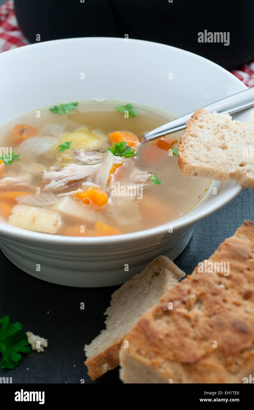 Homemade organic chicken and vegetable bouillon soup, served with bread