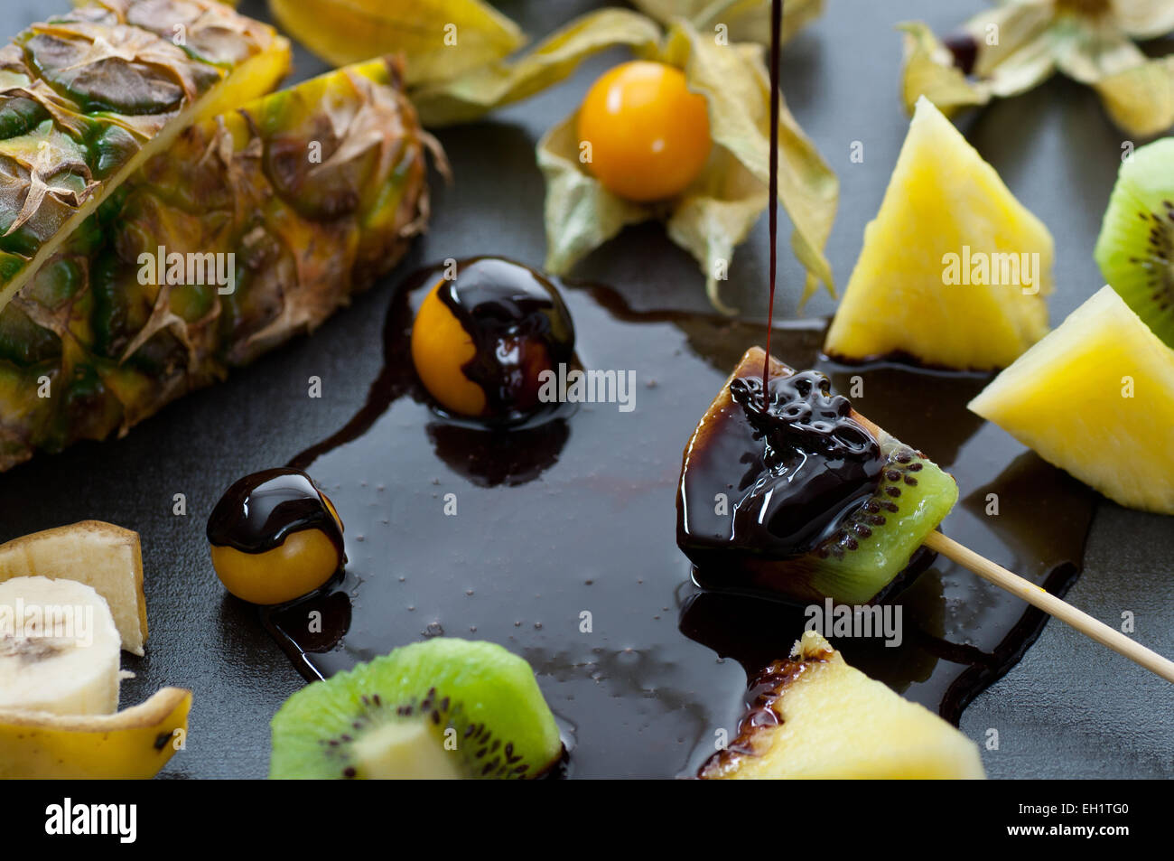 Fresh tropical fruits dipped in melted chocolate. Stock Photo