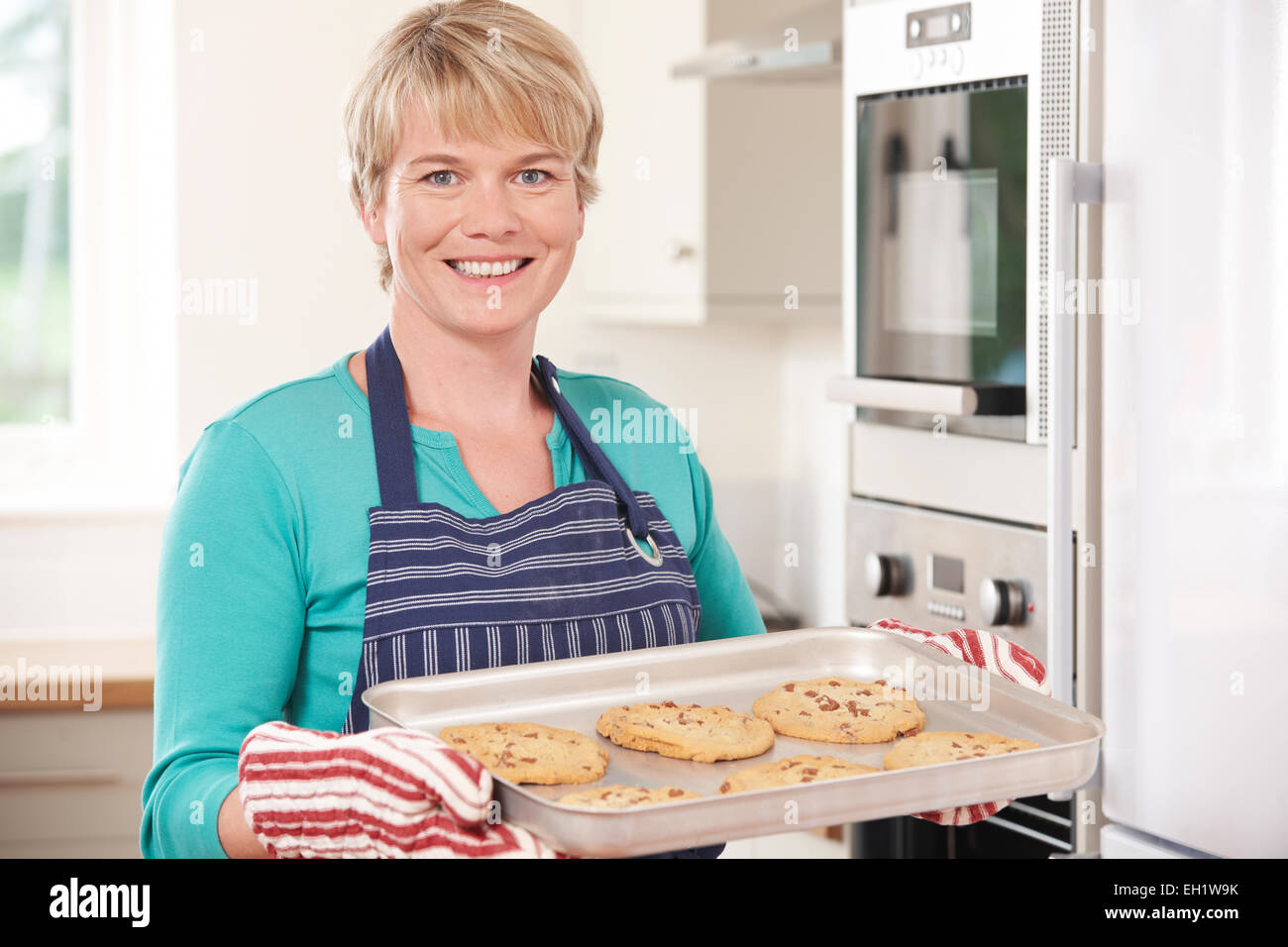 Woman In Kitchen Holding Tray With Home Baked Cookies Stock Photo