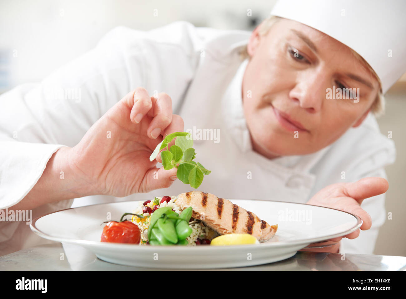 Chef Adding Garnish To Meal In Restaurant Kitchen Stock Photo