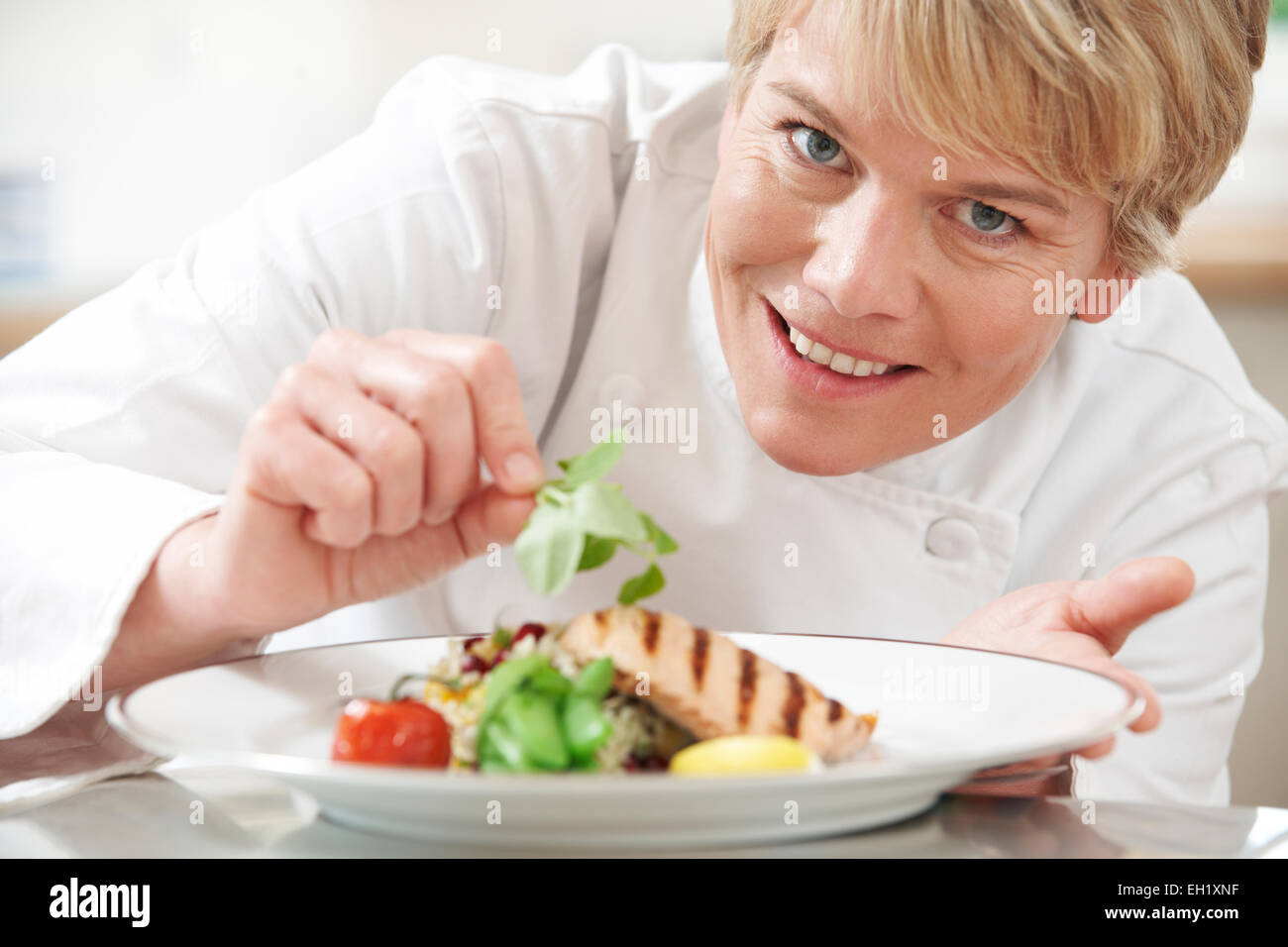 Chef Adding Garnish To Meal In Restaurant Kitchen Stock Photo