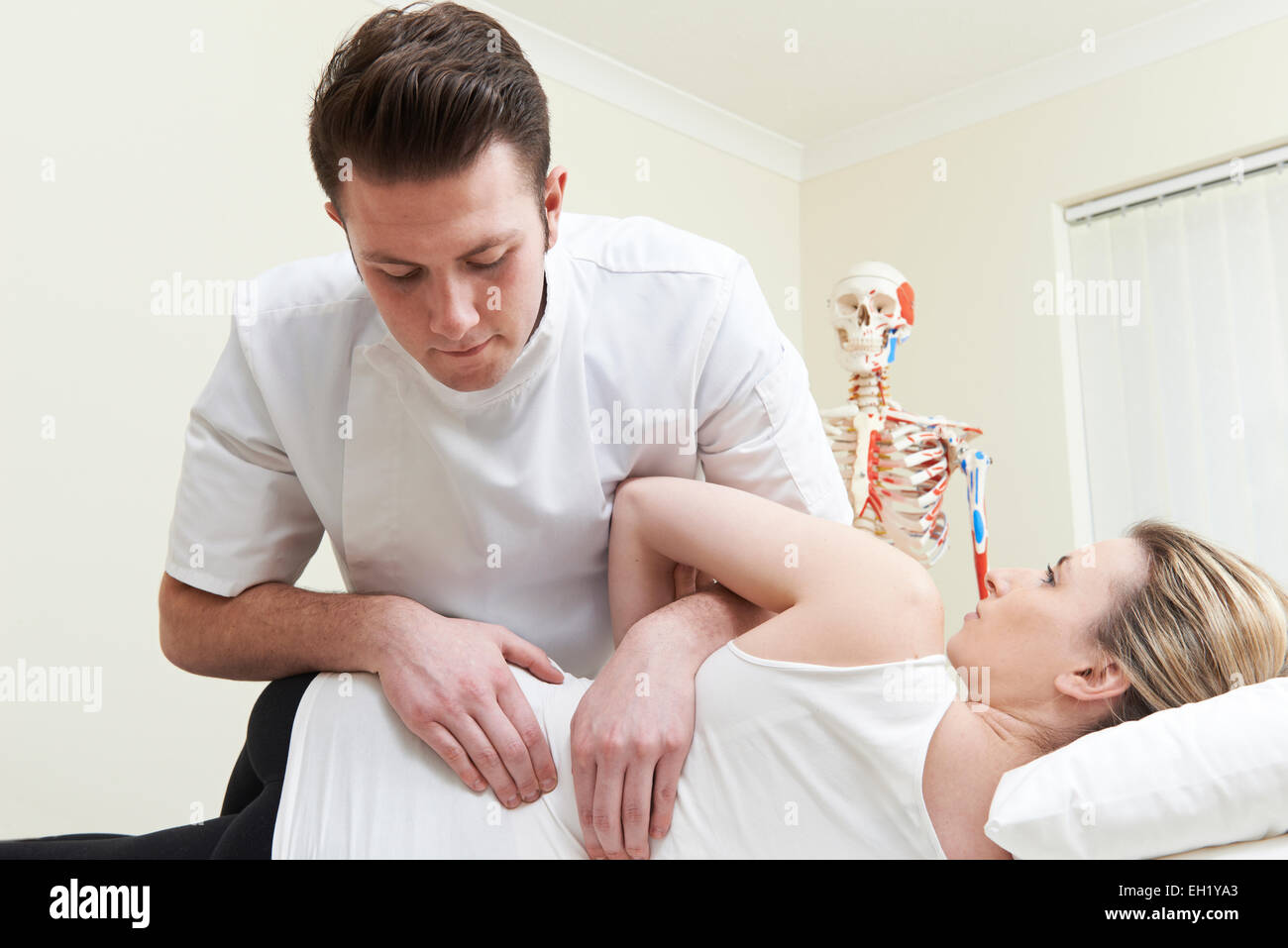 Male Osteopath Treating Female Patient With Back Problem Stock Photo