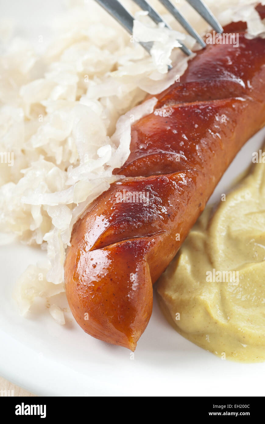 Bratwurst with sauerkraut and mustard. Stock Photo