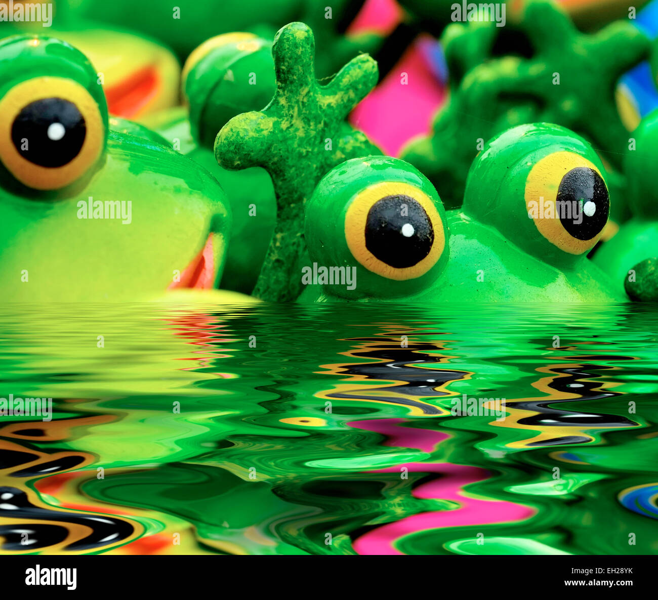 A group of ceramic frogs in a digitally created pool of water Stock Photo