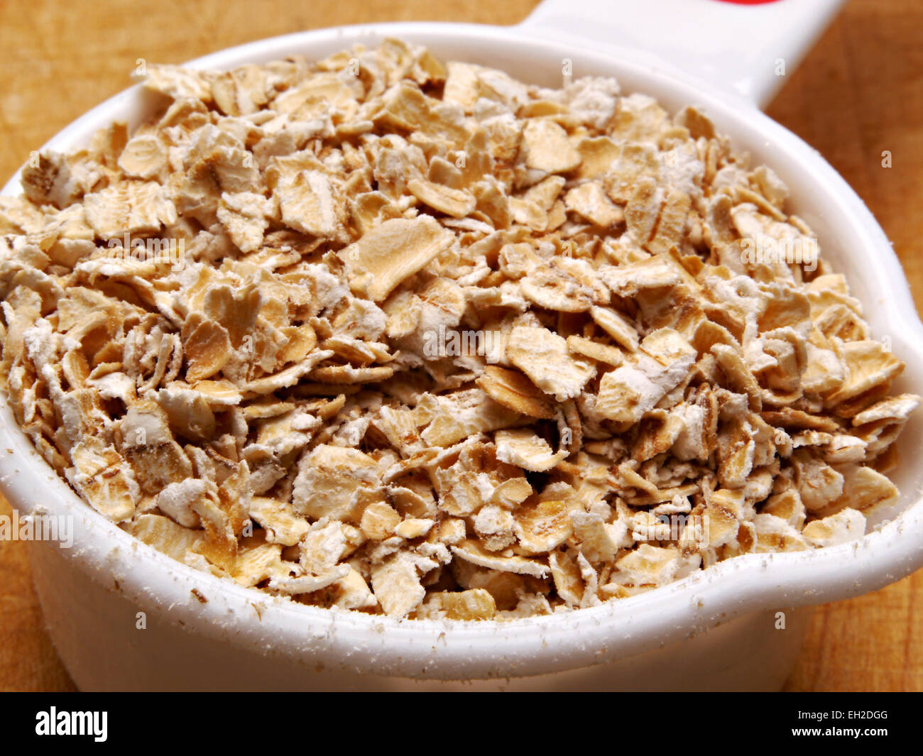 Uncooked oatmeal is sitting  in a white scoop. Stock Photo