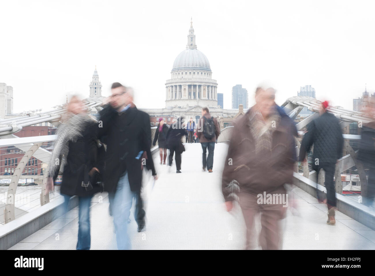 London, Motion blur of people walking across Millennium Bridge with St Pauls Cathedral in the background Stock Photo