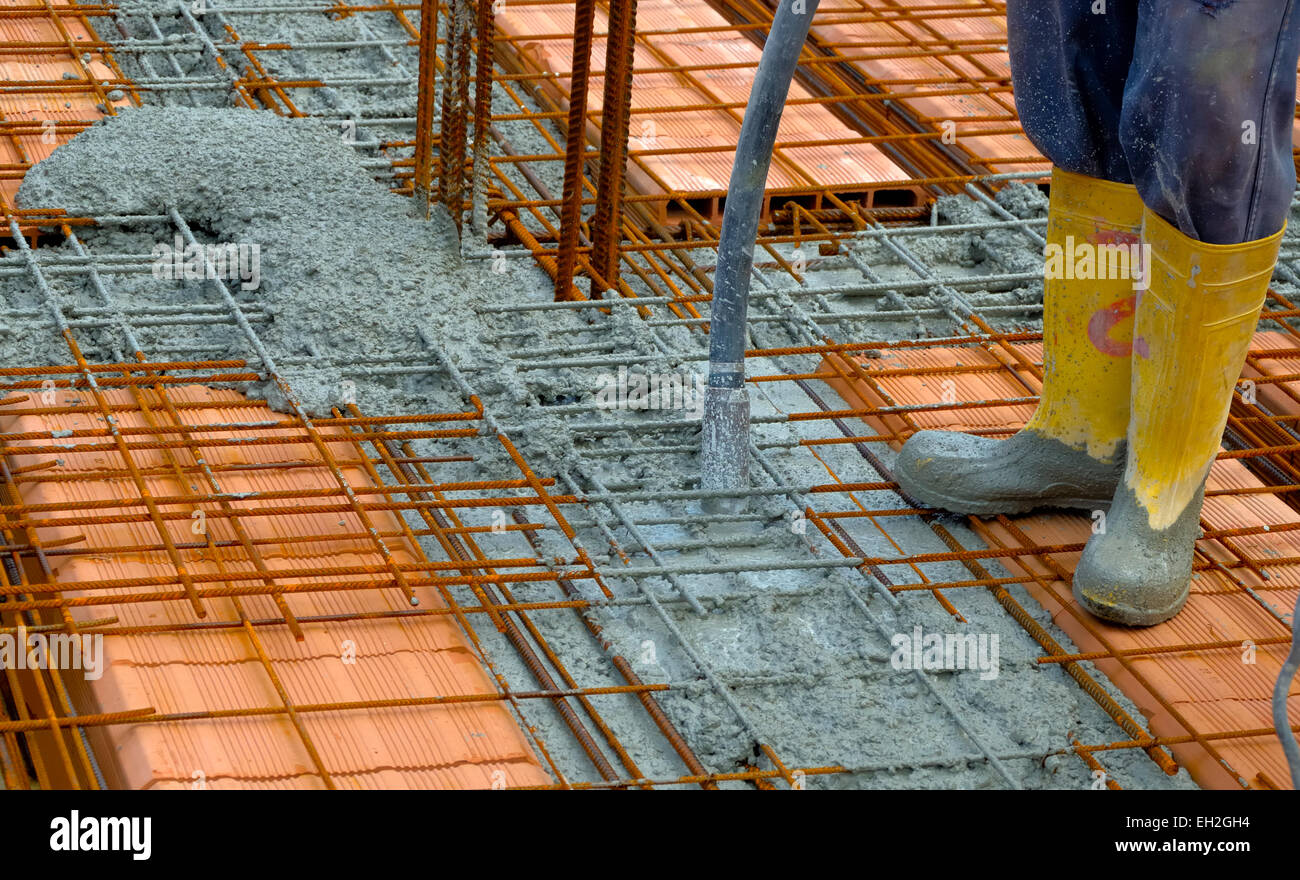 Construction worker compacting liquid cement in reinforcement form work ...