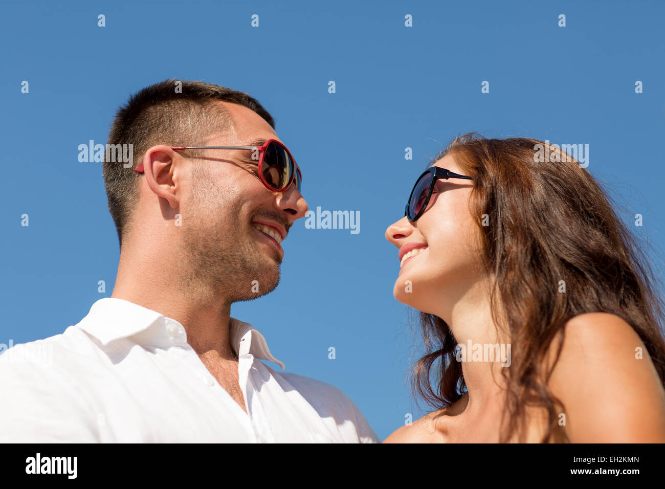 smiling couple over blue sky background Stock Photo - Alamy