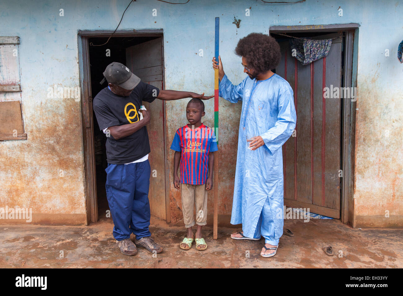 Bamenda, Cameroon, July 2013: A young boy is measured by Benoit Assou-Ekotto before receiving his treatment for river blindness. Stock Photo