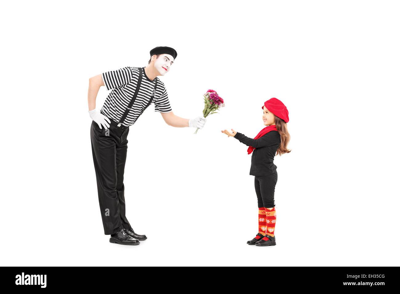 Full length portrait of a mime artist giving flowers to a little girl isolated on white background Stock Photo