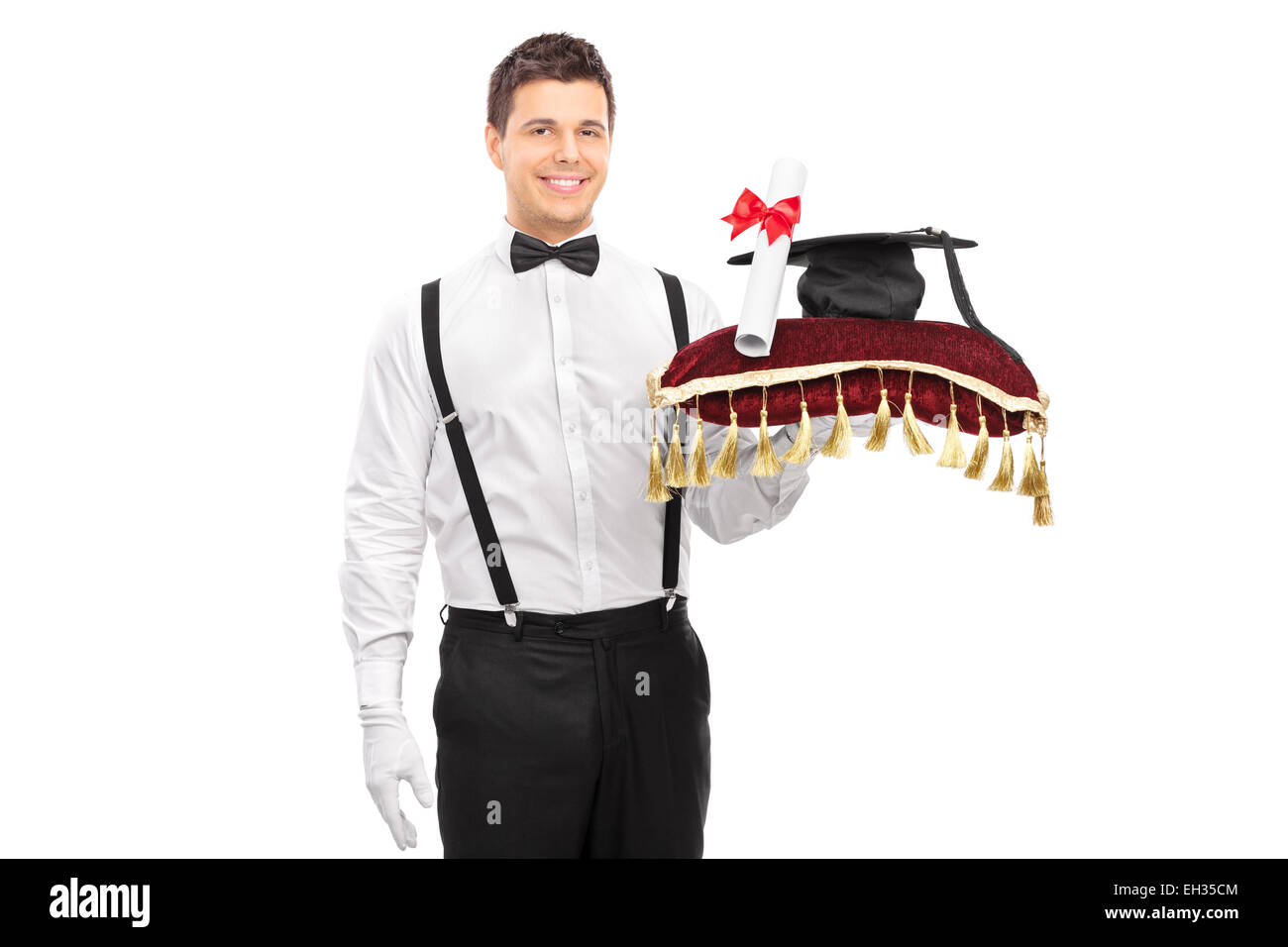 Male butler holding a diploma and a mortarboard on a red pillow isolated on white background Stock Photo