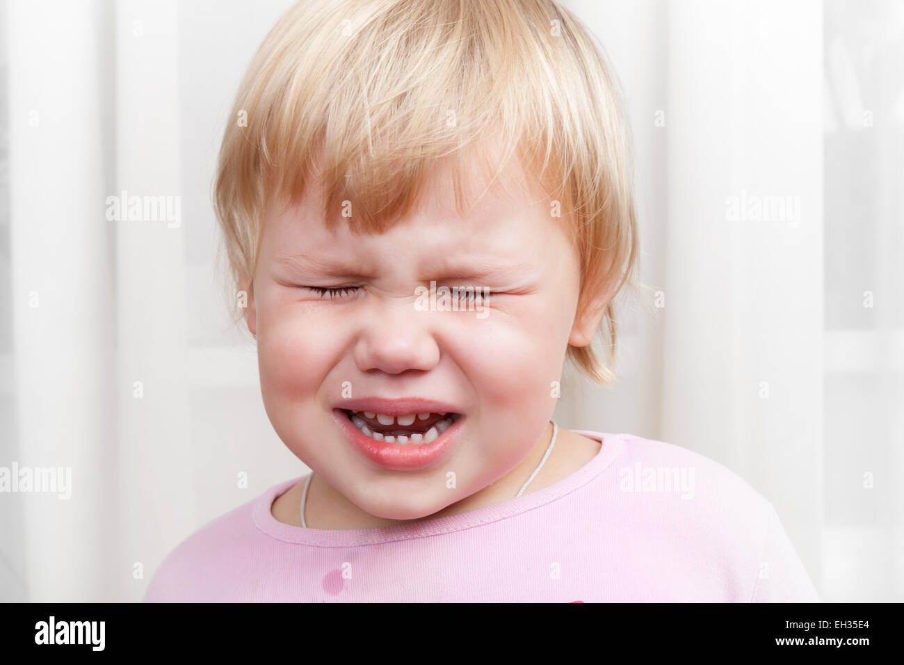 Closeup portrait of blonde crying Caucasian baby girl Stock Photo