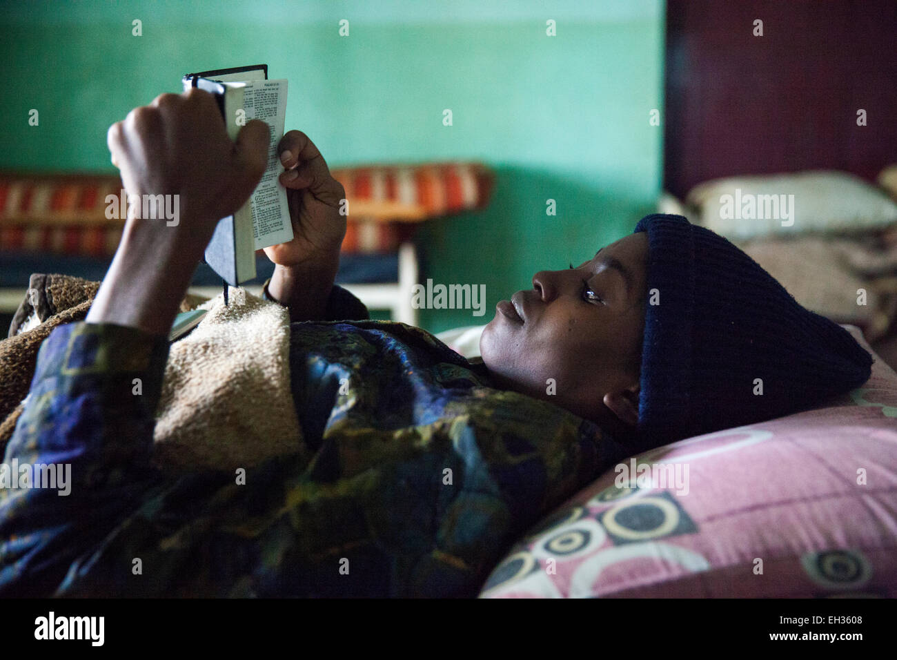 Bamenda, Cameroon, July 2013; A young woman, sick with a serious illness, reading the bible in a hospital bed. Stock Photo