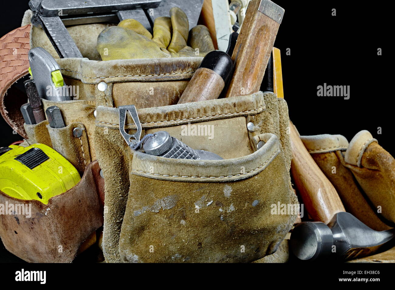 Rugged worn carpenters leather work bags and belt with construction tools and hammer isolated on