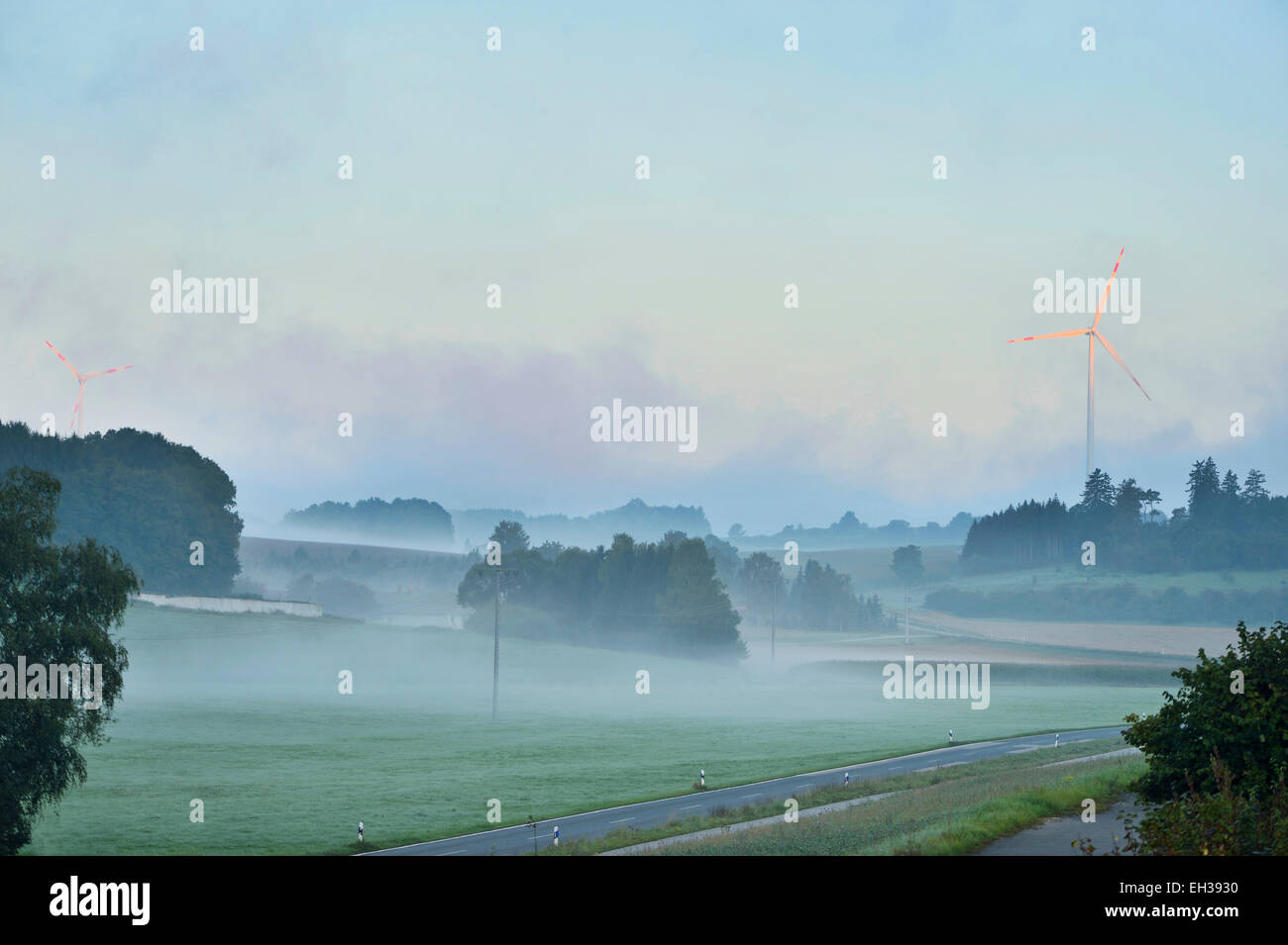 Scenic view of foggy farmland in the morning with wind turbine in background, Upper Palatinate, Bavaria, Germany Stock Photo