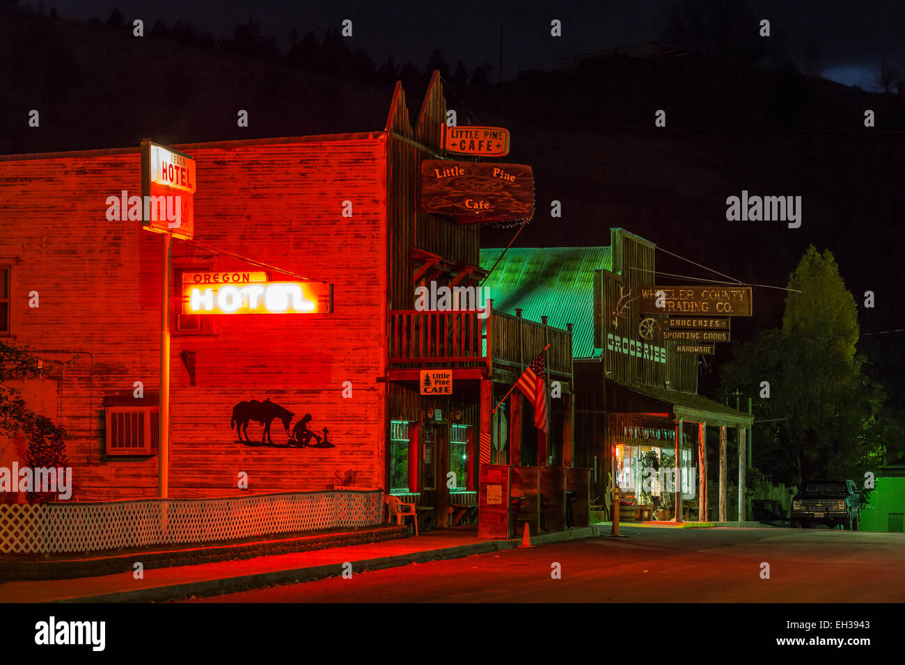Classic western streetscape at night, with a neon Oregon Hotel sign lighting the sides of a building, in Mitchell, Oregon, USA Stock Photo