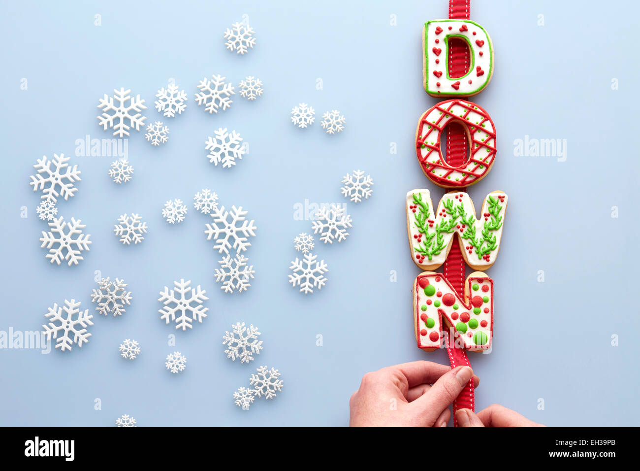 Overhead View of Decorated Christmas Cookies spelling DOWN on Blue Background with Snowflakes Stock Photo