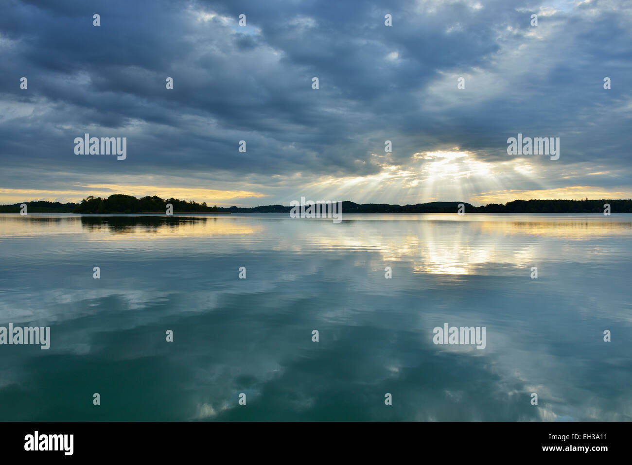 Clouds and crepuscular sunrays refelcted in lake at sunrise, Woerthsee Lake, Upper Bavaria, Fuenfseenland, Germany Stock Photo