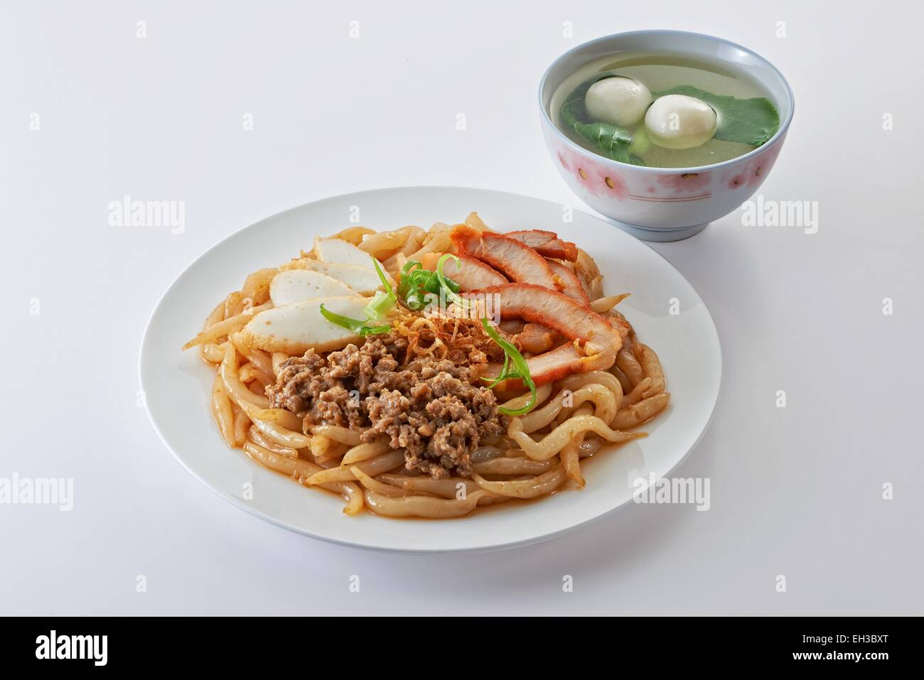 Fried noodle with roast pork sliced fish cake minced pork and fishball soup in clean background Stock Photo