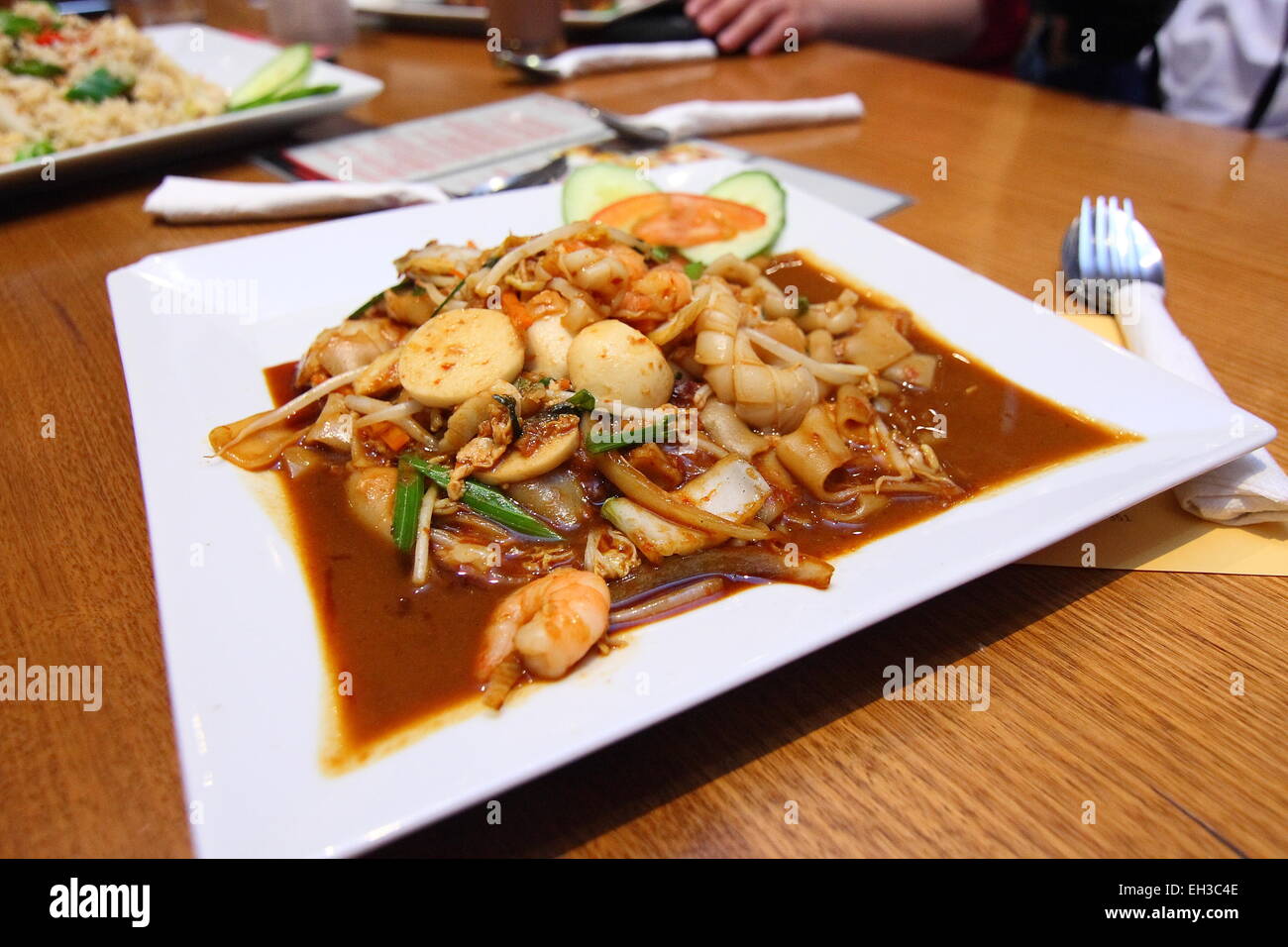 Freshly cooked Seafood flat noodles on white plate on wooden table Stock Photo